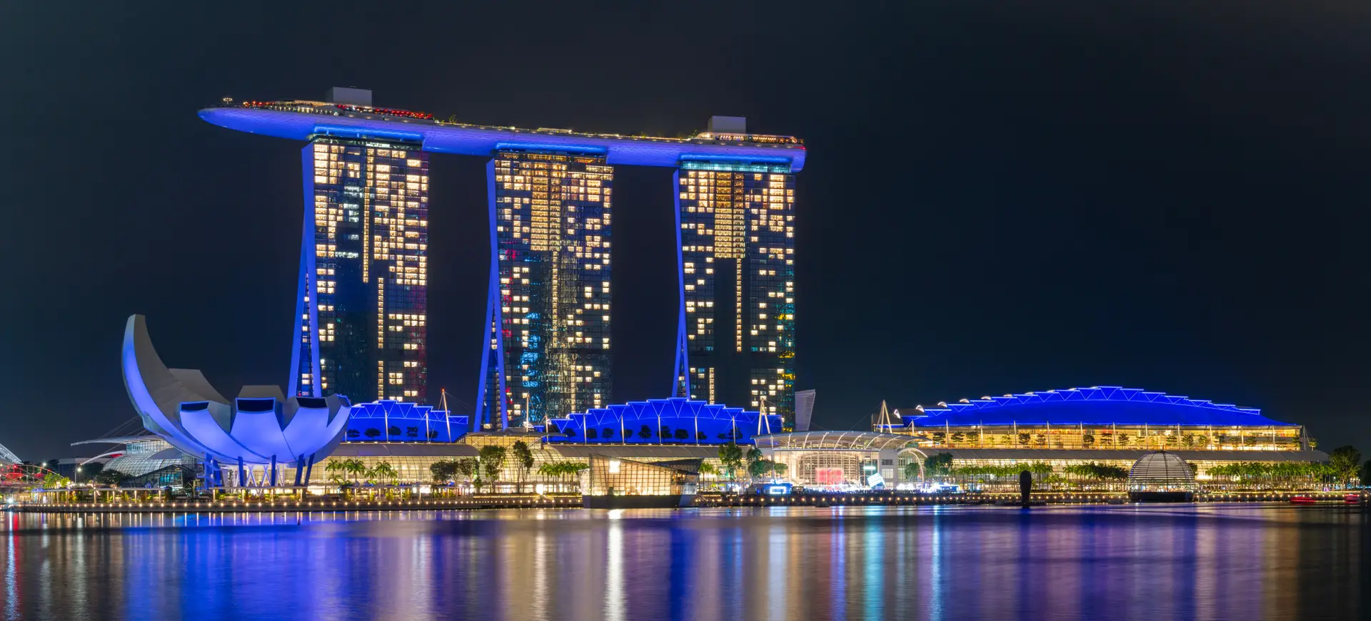 Illuminated waterfront casino destination reflecting across dusk waters